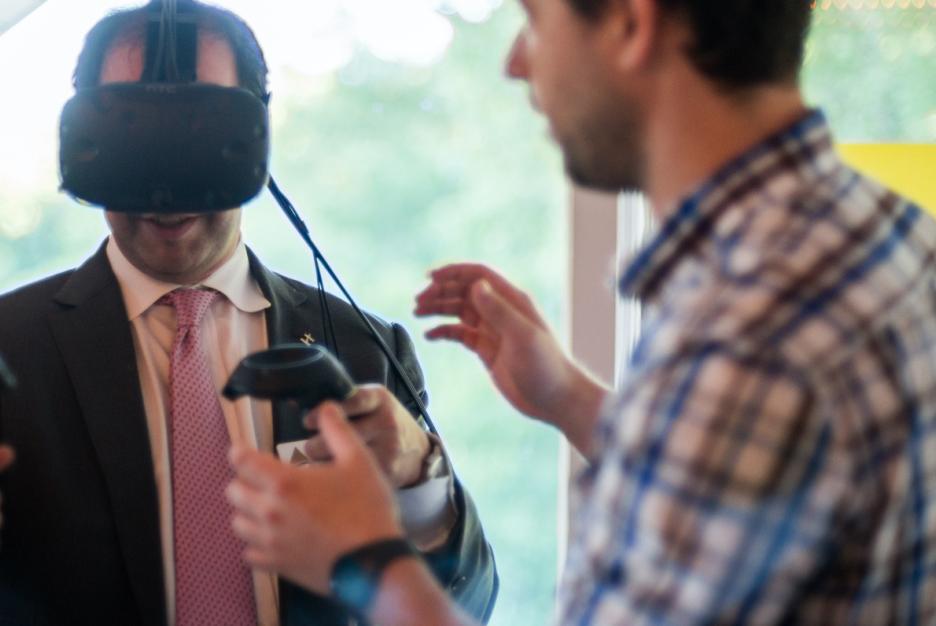 Primacy employee assisting someone wearing a VR headset, viewing Trading Ages VR experience